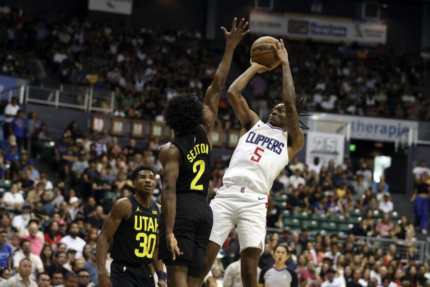 Los Angeles Clippers' Bones Hyland (5) shoots over Utah Jazz's Collin Sexton (2) during the third quarter of a preseason NBA basketball game, Sunday, Oct. 8, 2023, in Honolulu. (AP Photo/Marco Garcia)