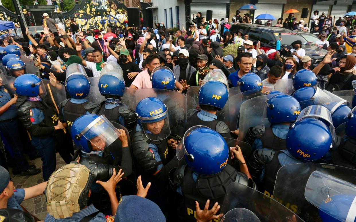 A press of people many wearing riot helmets and carrying shields