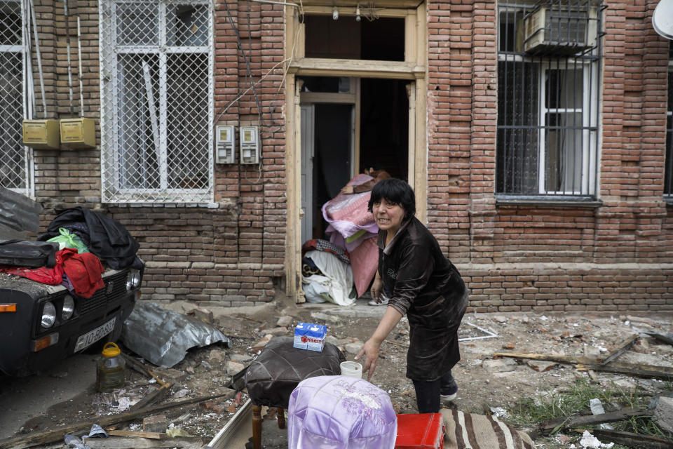 A woman, salvages belongings from a house damaged by shelling by Armenian forces, in a residential area of the city of Ganja, Azerbaijan's second-largest city, Monday, Oct. 5, 2020. The fighting between Armenian and Azerbaijani forces over the separatist territory of Nagorno-Karabakh resumed Monday, with both sides accusing each other of launching attacks. The region lies in Azerbaijan but has been under the control of ethnic Armenian forces backed by Armenia since the end of a separatist war in 1994. (Unal Cam/DHA via AP)