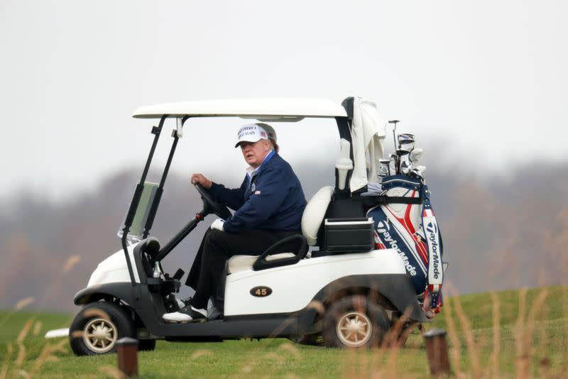 U.S. President Donald Trump drives a golf cart at the Trump National Golf Club in Sterling