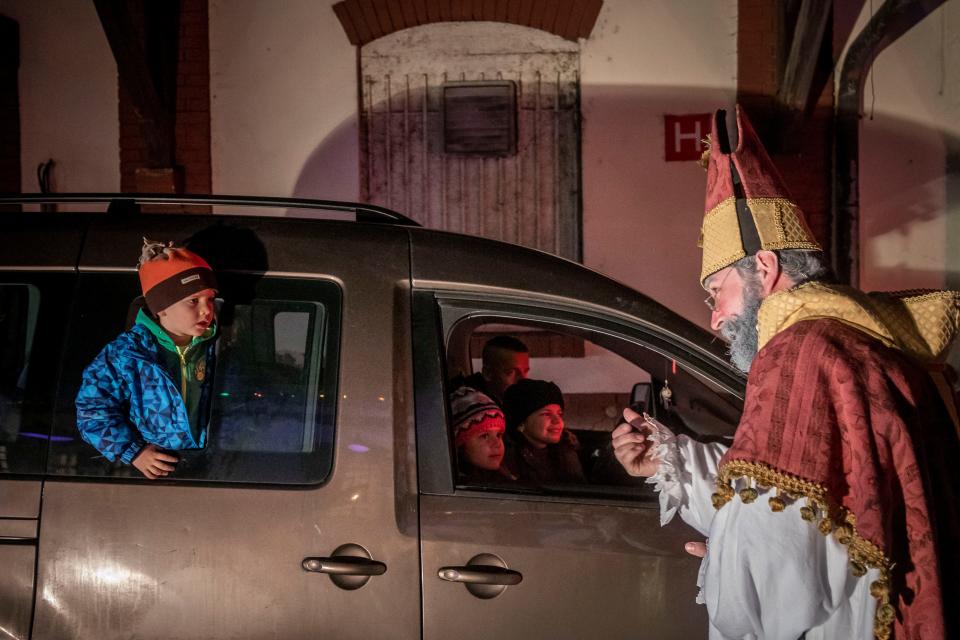 PRAGUE, CZECH REPUBLIC - DECEMBER 05: Members of the Cirk La Putyka troupe entertain people driving through with their cars on the eve of St. Nicholas Day on December 05, 2020 in Prague, Czech Republic. On the eve of St. Nicholas, Czechs traditionally celebrate by dressing up as Devils, Angels, and St. Nicholas, and visiting children, handing out little presents. Amid the coronavirus crisis, Circ La Putyka troupe offered a drive-thru celebration as spectators drove a route visiting heaven, hell, and St. Nicholas. Due to the governments restrictive measures, the usual traditions of door-to-door visiting would be impossible. The eager guests formed a long line of cars at the Circ La Putyka base in Prague. (Photo by Gabriel Kuchta/Getty Images)