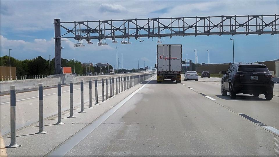 This southbound stretch of the I-295 managed lanes shows the reflective markers (left) separating them from the untolled interstate. An overhead gantry holds cameras to monitor cars in the toll lanes (upper left).