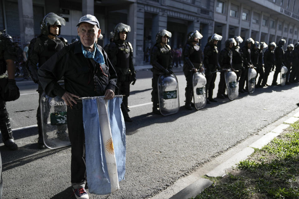 FILE- A retiree who said he voted for President Javier Milei stands in support of security forces deployed during protests against economic measures in downtown Buenos Aires, Argentina, Dec. 20, 2023. Milei has drastically cut spending to end the fiscal deficit and contain inflation of almost 161% annually, including devaluing the peso more than 50%, dismissing public employees, suspending public works and reducing transportation and energy subsidies. (AP Photo/Rodrigo Abd, File)