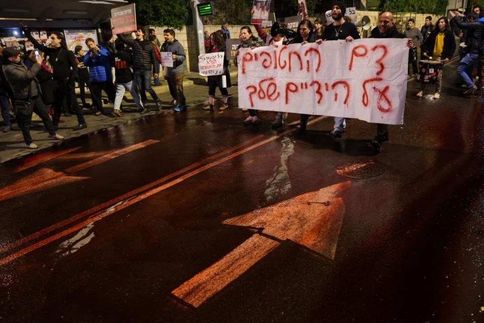 Protesters spill red paint on the road to symbolise the blood of the Israeli hostages held in Gaza since the 7 October attacks (Getty)