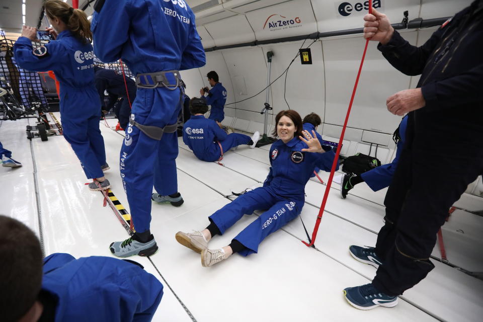 people in blue flight suits in the cabin of a plane with no seats