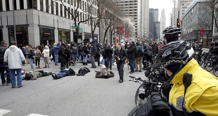 Chicago police officers watch as protesters march down Chicago's Michigan Avenue during a protest march against police violence in Chicago, Illinois December 24, 2015. REUTERS/Frank Polich