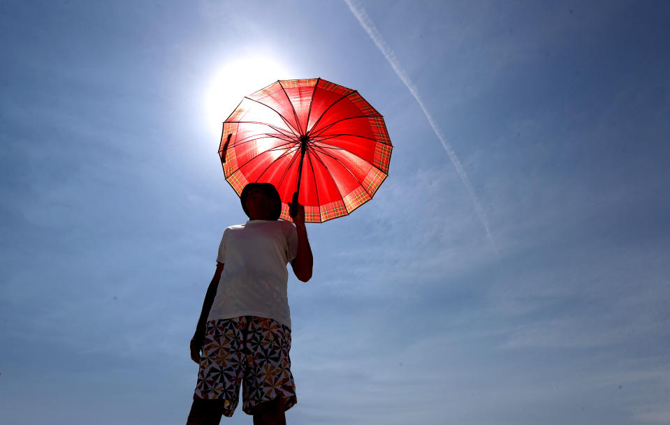 A man walks with an umbrella at Henley Beach during hot weather in Adelaide in November.