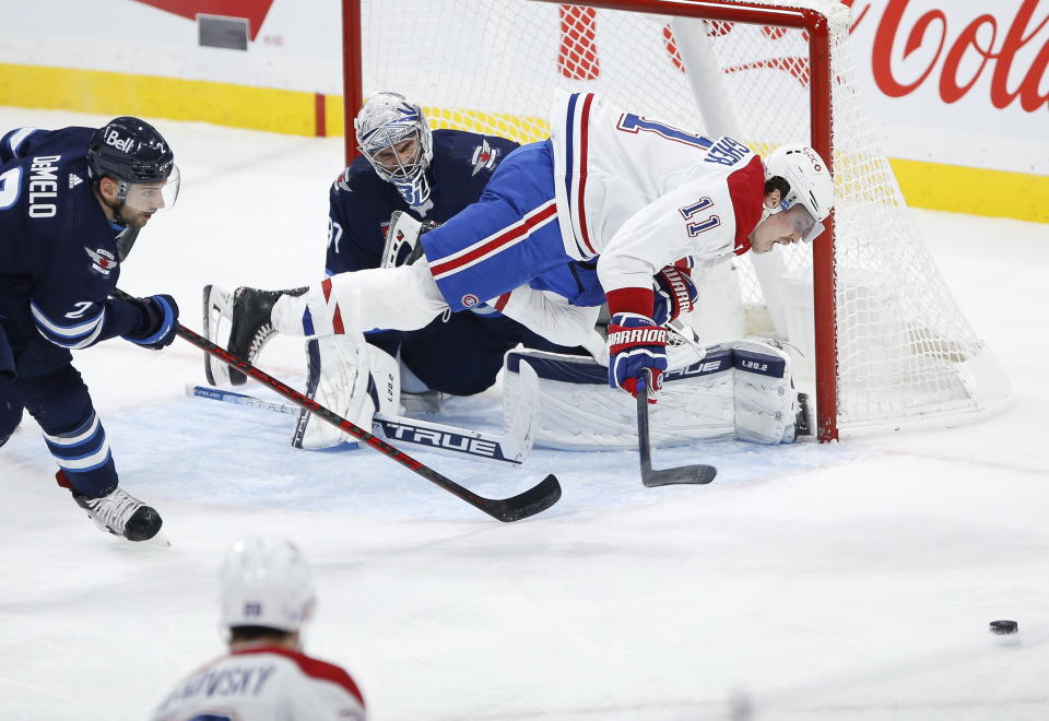 Montreal Canadiens' Brendan Gallagher (11) trips over Winnipeg Jets goaltender Connor Hellebuyck (37) as Jets' Dylan DeMelo (2) defends during third-period NHL hockey game action in Winnipeg, Manitoba, Thursday, Nov. 3, 2022. (John Woods/The Canadian Press via AP)