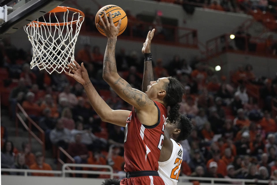 Texas Tech guard Jaylon Tyson, left, shoots in front of Oklahoma State forward Kalib Boone, right, in the second half of an NCAA college basketball game Wednesday, Feb. 8, 2023, in Stillwater, Okla. (AP Photo/Sue Ogrocki)