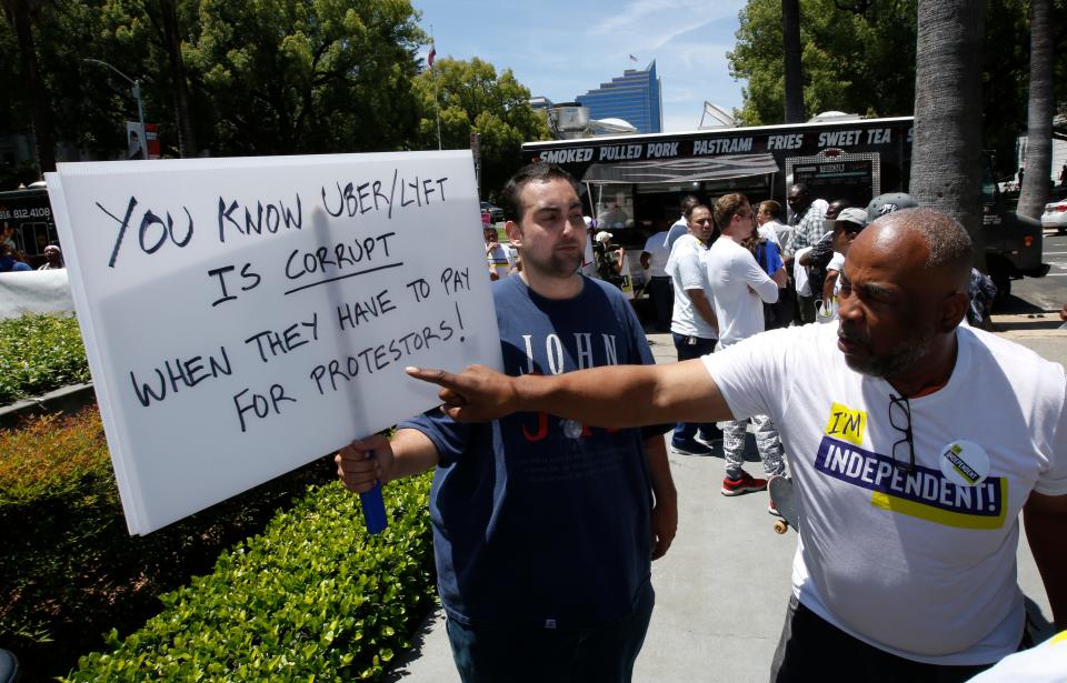 Ride-share driver Pierre Finley, right, a supporter of AB 5, a measure to limit when companies can label workers as independent contractors, questions Ruben Houghtailing, about his opposition to the bill, during a rally in Sacramento, Calif., on July 9.