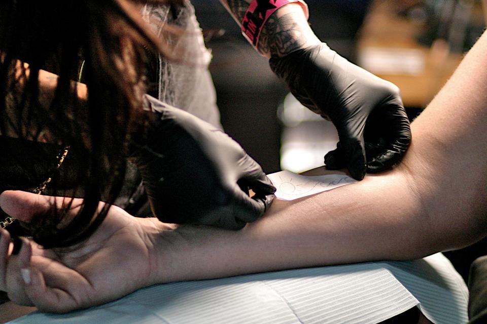 Ari Mastellino applies a tattoo design with transfer paper during the 2023 INKcarceration Music & Tattoo Festival.