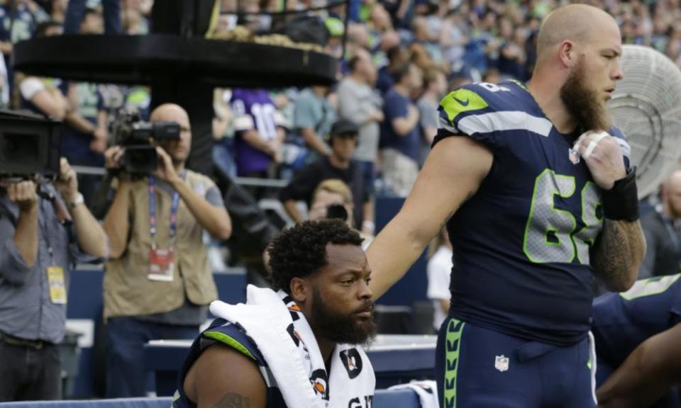 Michael Bennett sits for the national anthem as his team-mate Justin Britt gives a show of support