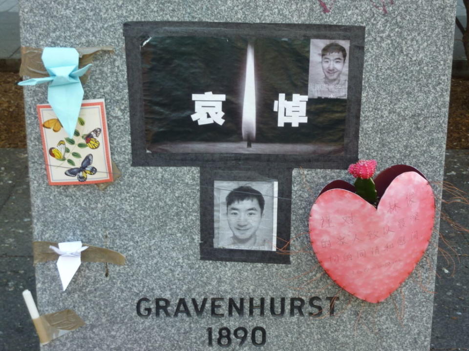 Gravestone with photos and heart-shaped tribute, adorned with ribbons and a floral card