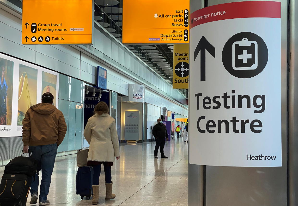 Travellers pass a sign for a COVID-19 test centre at Heathrow Airport, London, Britain, February 13, 2021. REUTERS/Toby Melville