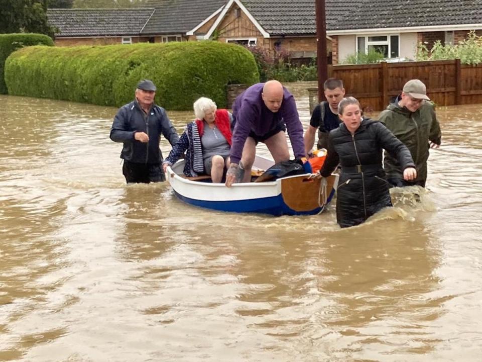 Locals use a homemade boat to rescue elderly residents from their homes in the village of Debenham, Suffolk, on Friday (PA)