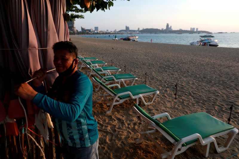 FILE PHOTO: Man collects his umbrellas on an almost empty beach in Pattaya