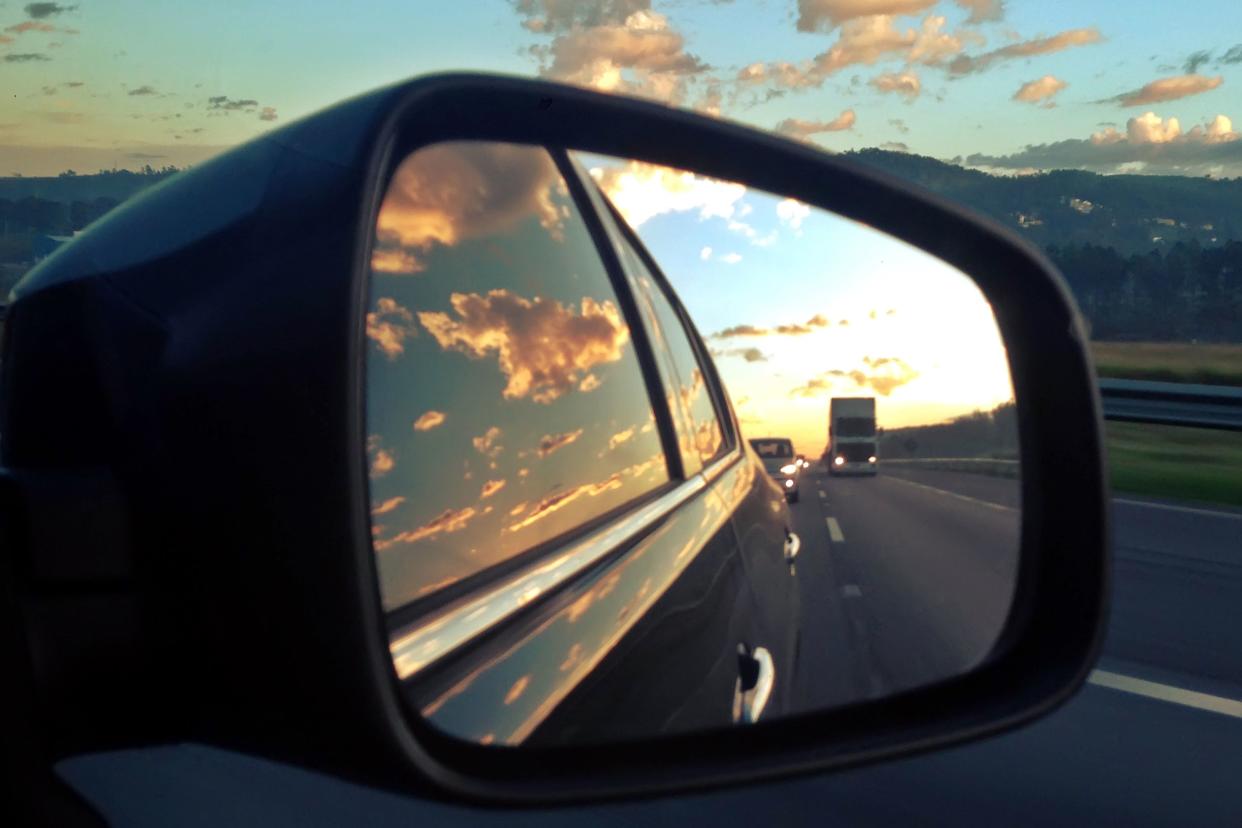 beautiful image of road at sunset by car rear view mirror