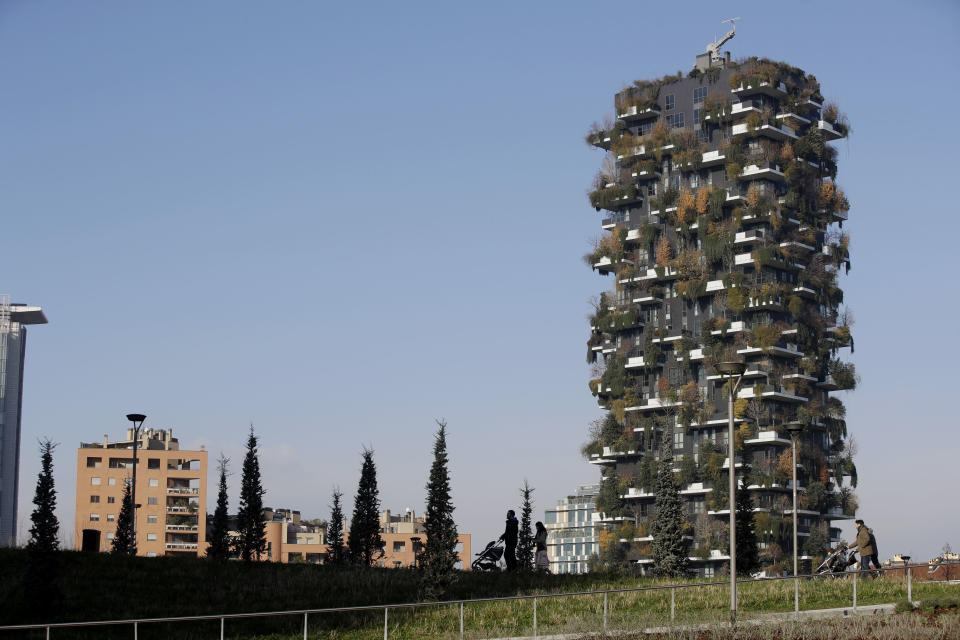 People walk through the Tree Library park in Milan, Italy, Sunday, Dec. 9, 2018. If Italy's fashion capital has a predominant color, it is gray not only because of the blocks of uninterrupted neoclassical stone buildings for which the city is celebrated, but also due to the often-gray sky that traps in pollution. The city has ambitious plans to plant 3 million new trees by 2030_ a move that experts say could offer relief to the city’s muggy and sometimes tropical weather. (AP Photo/Luca Bruno)