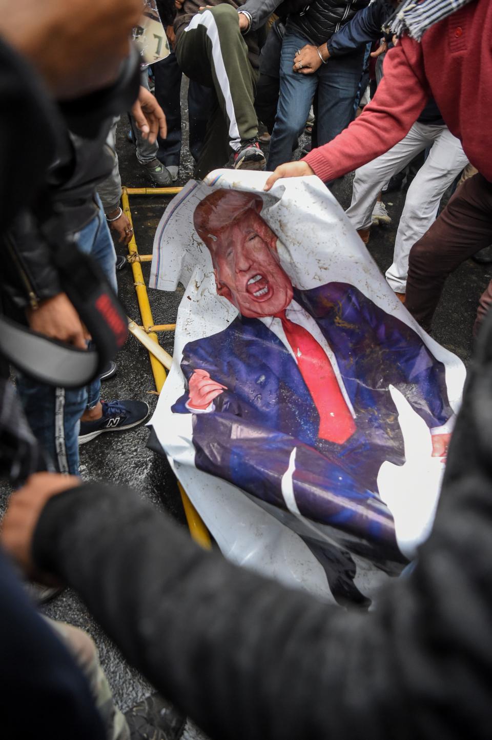 People leave a poster representing US President Donald Trump (C) on the ground to protest against the US authorities for the killing of Iranian commander Qasem Soleimani in Iraq, during a demonstration near the US embassy in New Delhi on January 7, 2020. - A US drone strike killed top Iranian commander Qasem Soleimani at Baghdad's international airport on January 3, dramatically heightening regional tensions and prompting arch enemy Tehran to vow "revenge". (Photo by Prakash SINGH / AFP) (Photo by PRAKASH SINGH/AFP via Getty Images)