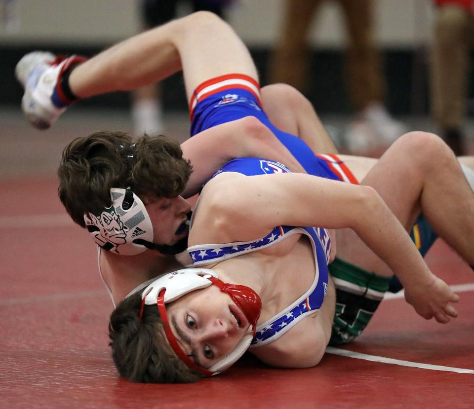 Aurora's Luke Green, top, flips over Revere's Brandon Brinker during their 120 pound match during the Division II district wrestling meet at Perry High School, Friday, March 4, 2022, in Perry, Ohio. [Jeff Lange/Beacon Journal]