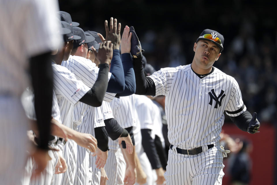 New York Yankees left fielder Giancarlo Stanton is greeted by teammates while lining up on the first base line prior to an opening day baseball game against the Baltimore Orioles at Yankee Stadium, Thursday, March 28, 2019, in New York. (AP Photo/Julio Cortez)