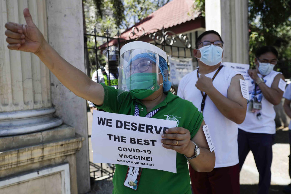 FILE - In this Friday, Feb. 26, 2021 file photo, a health worker wearing a face mask and shield holds a sign as she and others call on the government to give them a vaccine with the safest, highest efficacy and effectivity during a a protest outside the Philippine General Hospital in Manila, Philippines. The group is opposing a plan by the government to have health workers vaccinated with China's Sinovac. (AP Photo/Aaron Favila)