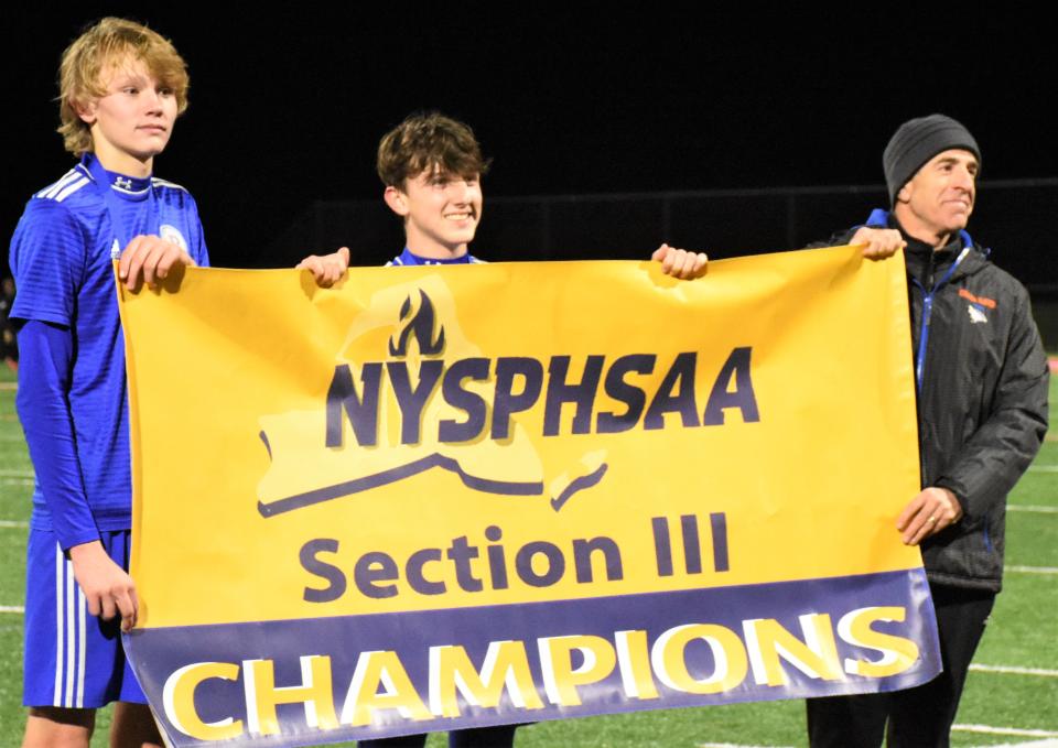 Poland captains Carter Cookinham and Jason Victor, and coach Greg Haver hold up the Section III championship banner.