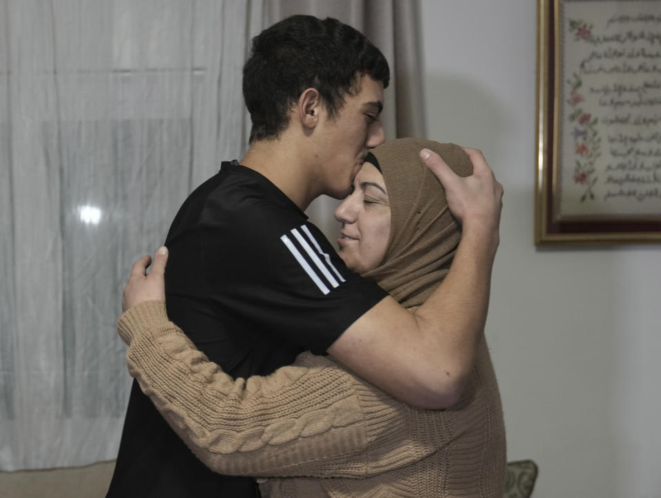 Released Palestinian prisoner Muhammad Abu Al-Humus, 17, hugs his mother after arriving home in the east Jerusalem neighborhood of Issawiya, Tuesday Nov. 28, 2023. Eleven Israeli women and children, freed by Hamas, entered Israel Monday night in the fourth swap under the original four-day truce, which began Friday and had been due to run out. Qatar said Israel was to release 33 Palestinians from its prisons, mostly teenagers. (AP Photo/Mahmoud Illean)