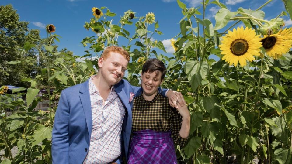 natalie beach and her husband stand among sunflower stalks on their wedding day