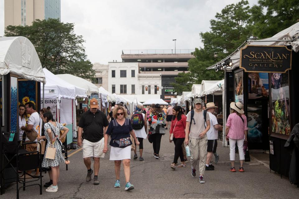 Visitors walk by booths on North University Avenue during the annual Ann Arbor Art Fair at U-M's central campus in Ann Arbor on Thursday, July 20, 2023.