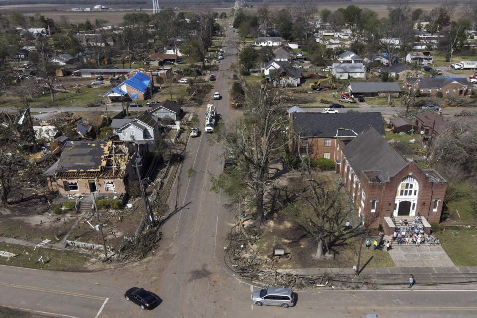 People worship on the steps of the Rolling Fork United Methodist Church, right, as damage is visible to surrounding properties, Sunday, March 26, 2023, in Rolling Fork, Miss. Emergency officials in Mississippi say several people have been killed by tornadoes that tore through the state on Friday night, destroying buildings and knocking out power as severe weather produced hail the size of golf balls moved through several southern states. (AP Photo/Julio Cortez)