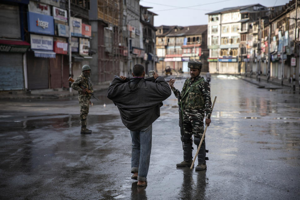 FILE - An Indian paramilitary soldier orders a Kashmiri to open his jacket before frisking him during curfew, days after New Delhi revoked the special status of Jammu and Kashmir, in Srinagar, Indian controlled Kashmir, Aug. 8, 2019. As India, the world’s largest democracy, celebrates 75 years of independence on Aug. 15, 2022, its independent judiciary, diverse media and minorities are buckling under the strain, putting its democracy under pressure. (AP Photo/Dar Yasin, File)