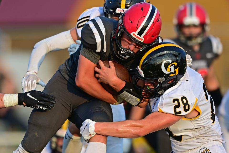 Cardinal's Joshua Soltis is tackled by Garfield's Jesse Grace during the first half of their game Sunday night at Cardinal High School.