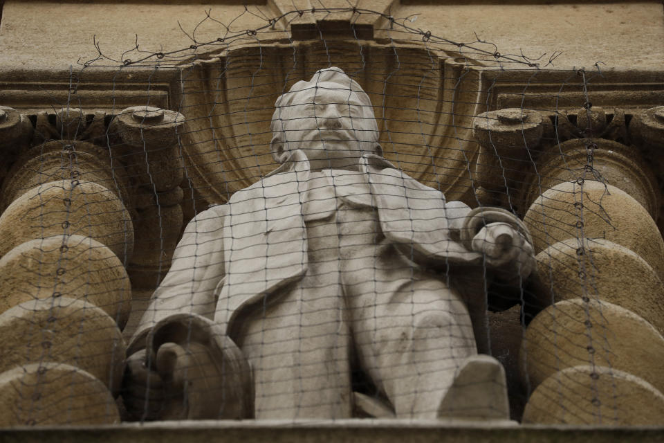 A statue of Cecil Rhodes, the controversial Victorian imperialist who supported apartheid-style measures in southern Africa stands mounted on the facade of Oriel College in Oxford, England, Wednesday, June 17, 2020. The governing body of Oriel College are meeting today to discuss the future of the statue. (AP Photo/Matt Dunham)