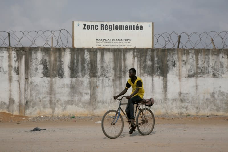 A cyclist drives pasts the wall of the Felix Houphouet Boigny airport in Abidjan