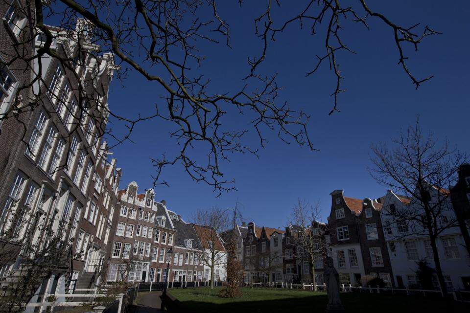 This March 12, 2013 photo shows a view of Begijnhof courtyard in Amsterdam. The clatter of trams and ringing of bicycle bells can be an assault on the ears, but there's a hidden oasis of peace in the heart of Amsterdam if you need a little quiet time. The Begijnhof is a small grassed courtyard surrounded by beautiful 17th- and 18th-century houses that were originally built for pious Catholic single women. It's right in the middle of town and reachable by a gateway at the end of a lane leading off one of the city's busiest shopping streets, but it is almost eerily silent. (AP Photo/Peter Dejong)