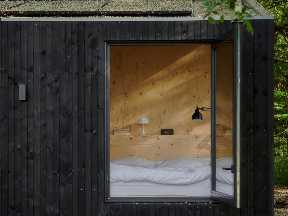 A look inside a Raus cabin with a bed near an open window.