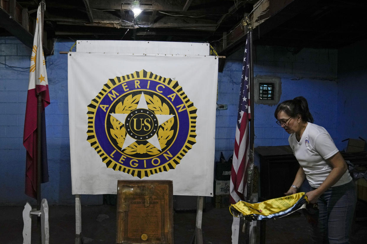 A staff member arranges banners beside the Philippine and U.S. flag at the American Legion Post 4 just outside what used to be America's largest overseas naval base at Olongapo city, Zambales province, northwest of Manila, Philippines on Monday Feb. 6, 2023. The U.S. has been rebuilding its military might in the Philippines after more than 30 years and reinforcing an arc of military alliances in Asia in a starkly different post-Cold War era when the perceived new regional threat is an increasingly belligerent China. (AP Photo/Aaron Favila)