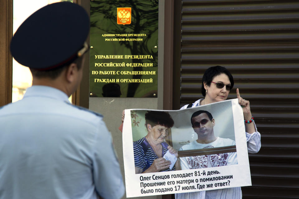 A woman holds a poster reading "Oleg Sentsov is on hunger strike for the 81st day. His mother lodged a petition for pardon on July 17, 2018, Where's the answer?" during a one-person picket in support of the jailed Ukrainian filmmaker in front of Russian President administration entrance in Moscow, Russia, Thursday, Aug. 2, 2018. Thursday marked the 81st day that Oleg Sentsov has been refusing food in a Russian prison. Sentsov is demanding that he and 64 other Ukrainians imprisoned in Russia whom he calls political prisoners be released. (AP Photo/Alexander Zemlianichenko)