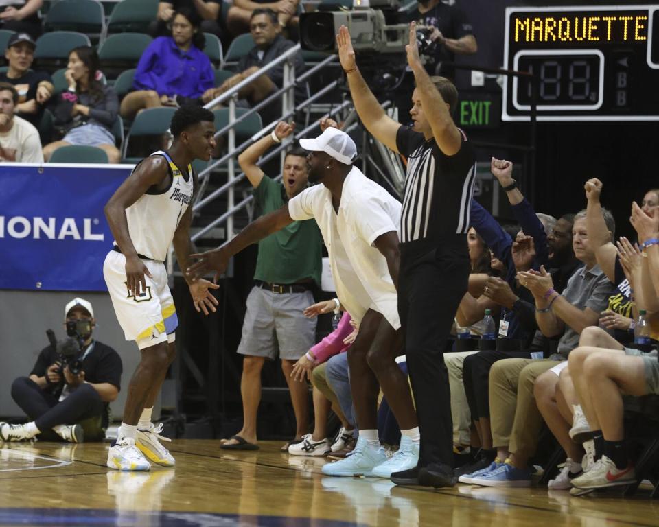 Dwyane Wade jumps up to congratulate Marquette's Kam Jones.