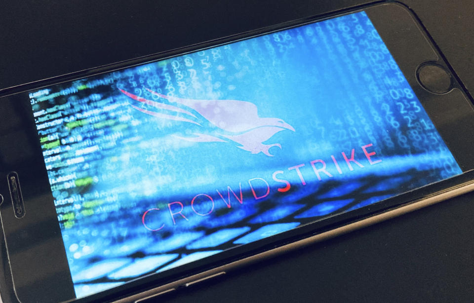 An iphone with blurred code and the Crowdstrike Falcon Pro logo. (Source: AP)