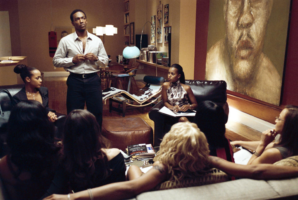 Anthony Mackie stands addressing a group of seated women in an indoor setting