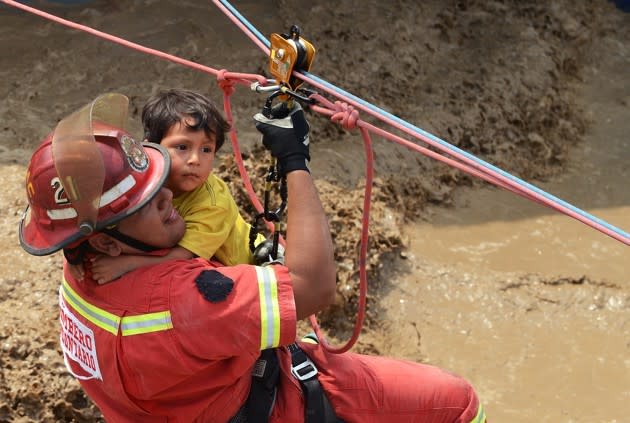 A rescue worker carries a child to safety over a flooded area in Peru’s Huachipa district on March 17, 2017. After heavy rains, Peru is experiencing its worst flash flooding in decades. <a href="https://www.theatlantic.com/photo/2017/03/peru-suffers-worst-flooding-in-decades/520146/" rel="nofollow noopener" target="_blank" data-ylk="slk:More photos here;elm:context_link;itc:0;sec:content-canvas" class="link ">More photos here</a>. (Cris Bouroncle / AFP / Getty)