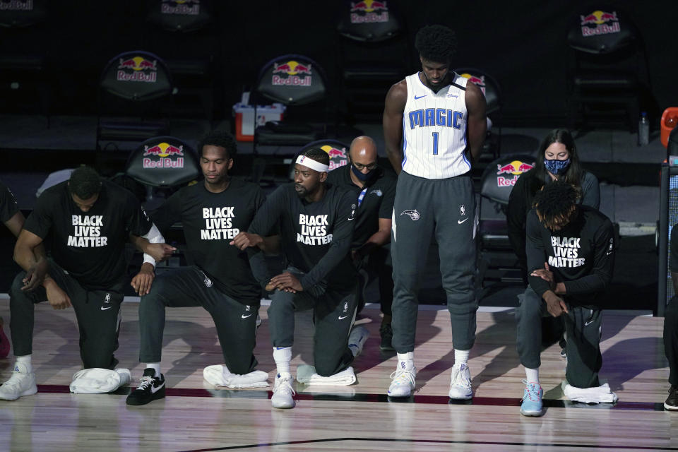 Orlando Magic's Jonathan Isaac (1) stands as others kneel before the start of an NBA basketball game between the Brooklyn Nets and the Orlando Magic Friday, July 31, 2020, in Lake Buena Vista, Fla. (AP Photo/Ashley Landis, Pool)