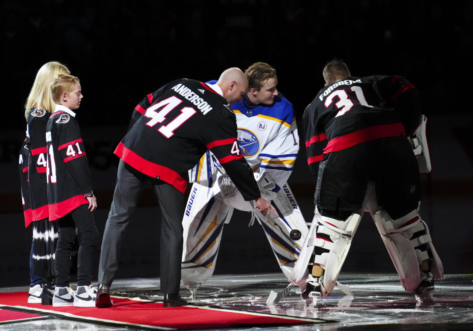 Former Ottawa Senators goaltender Craig Anderson is joined by his family as he takes part in a ceremonial puck drop with Senators goaltender Anton Forsberg (31) and Buffalo Sabres goaltender Ukko-Pekka Luukkonen (1) to mark his retirement, before an NHL hockey game Tuesday, Oct. 24. 2023, in Ottawa, Ontario. (Sean Kilpatrick/The Canadian Press via AP)