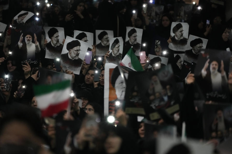 Mourners hold up a posters of the late Iranian President Ebrahim Raisi at the mam Khomeini Grand Mosque in Tehran, Iran, Tuesday, May 21, 2024, during a funeral ceremony for him and his companions who were killed in a helicopter crash on Sunday in a mountainous region of the country's northwest. Mourners in black began gathering Tuesday for days of funerals and processions for Iran's late president, foreign minister and others killed in a helicopter crash, a government-led series of ceremonies aimed at both honoring the dead and projecting strength in an unsettled Middle East. (AP Photo/Vahid Salemi)