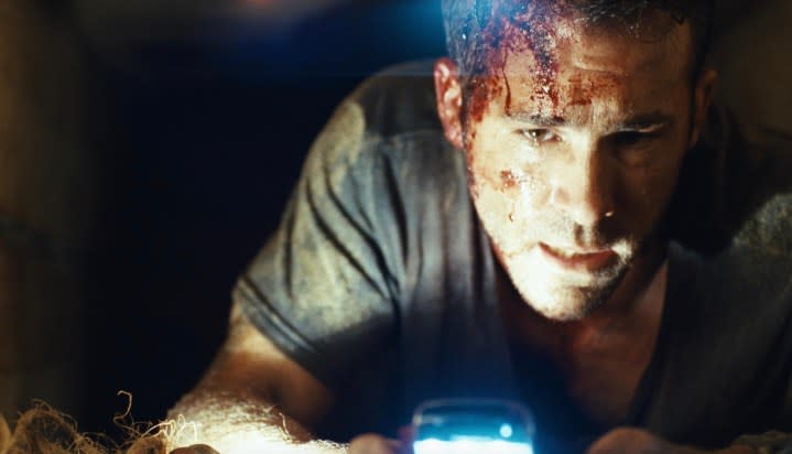 A man bleeding from his head holds a phone for light.