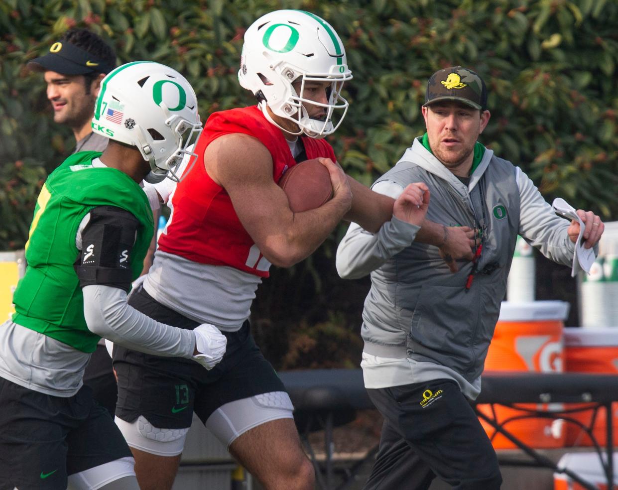 Oregon offensive coordinator and quarterbacks coach Will Stein, right, participates in a drill with defensive back Steve Stephens IV and quarterback Ty Thompson on the first practice of spring for Oregon football as they prepare for the 2023 season.