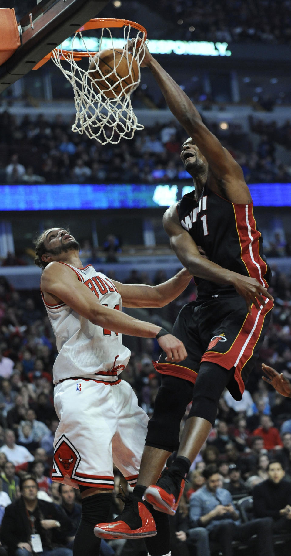 Miami Heat's Chris Bosh (1) dunks over Chicago Bulls Joakim Noah during the first quarter of an NBA basketball game in Chicago, Sunday, March 9, 2014. (AP Photo/ Paul Beaty)