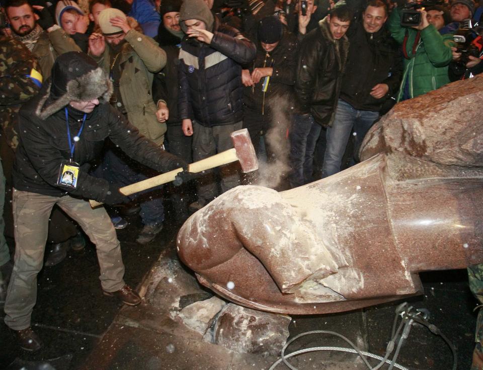 A man holds a sledgehammer as he smashes a statue of Soviet state founder Vladimir Lenin, which was toppled by protesters, during a rally organized by supporters of EU integration in Kiev, December 8, 2013. Crowds toppled a statue of Soviet state founder Vladimir Lenin in the Ukrainian capital and attacked it with hammers on Sunday in the latest mass protests against President Viktor Yanukovich and his plans for closer ties with Russia. REUTERS/Gleb Garanich (UKRAINE - Tags: POLITICS CIVIL UNREST)